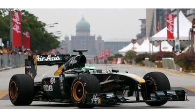 Jentera Formula 1 Lotus Racing beraksi di jalan raya Putrajaya berlatarbelakangkan Perdana Putra