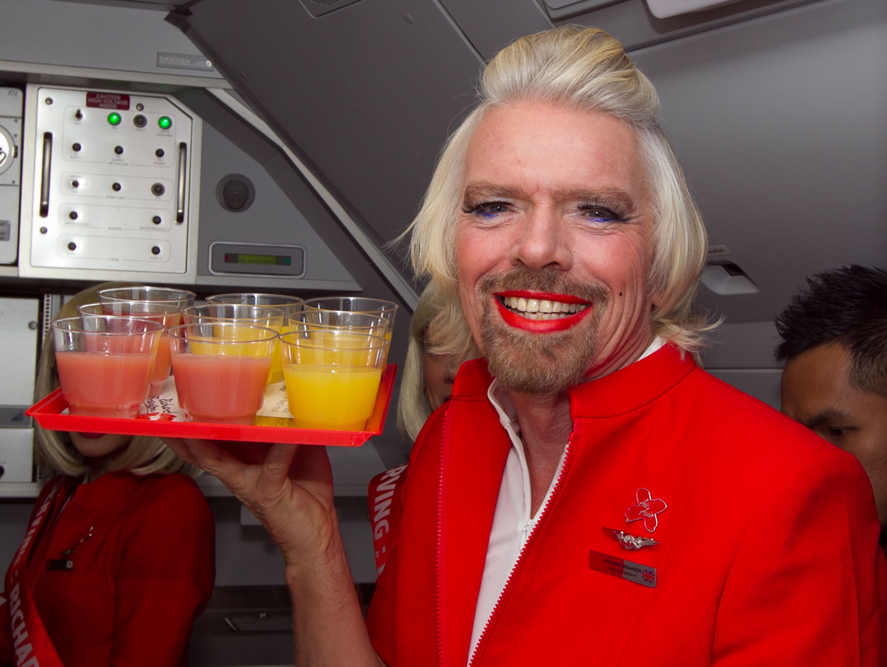 Richard Branson bersolek tebal dan bergincu merah menatang minuman dalam kabin