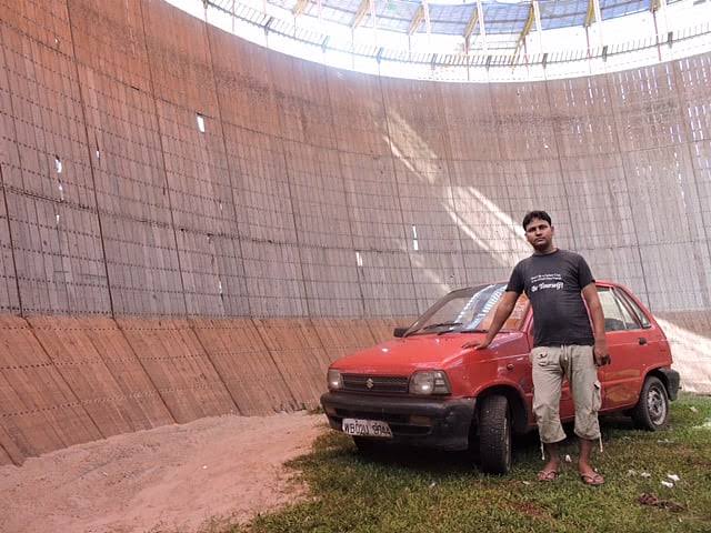 Pemandu berdiri di dasar telaga kayu bersebelahan kereta Maruti 800