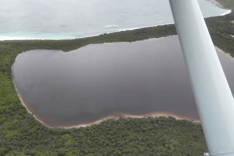 Pemandangan dari tingkap pesawat memaparkan Lake Hillier yang bertukar pudar kelabu