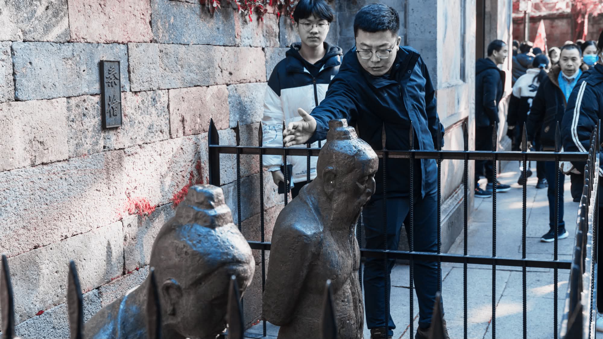 Orang ramai berkumpul menyentuh dan menepuk patung besi pasangan Qin Hui di Hangzhou